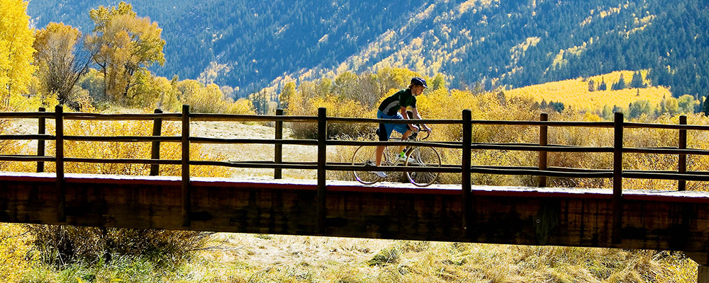 A Dancing Bear Aspen fractional owner bikes over a bridge on a gorgeous autumn day.