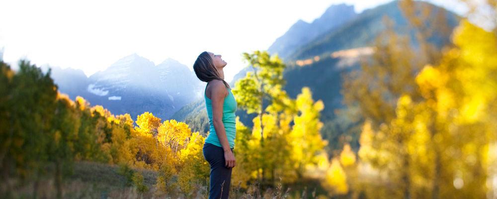 A pretty hiker takes a deep breathe standing atop the Aspen mountains.